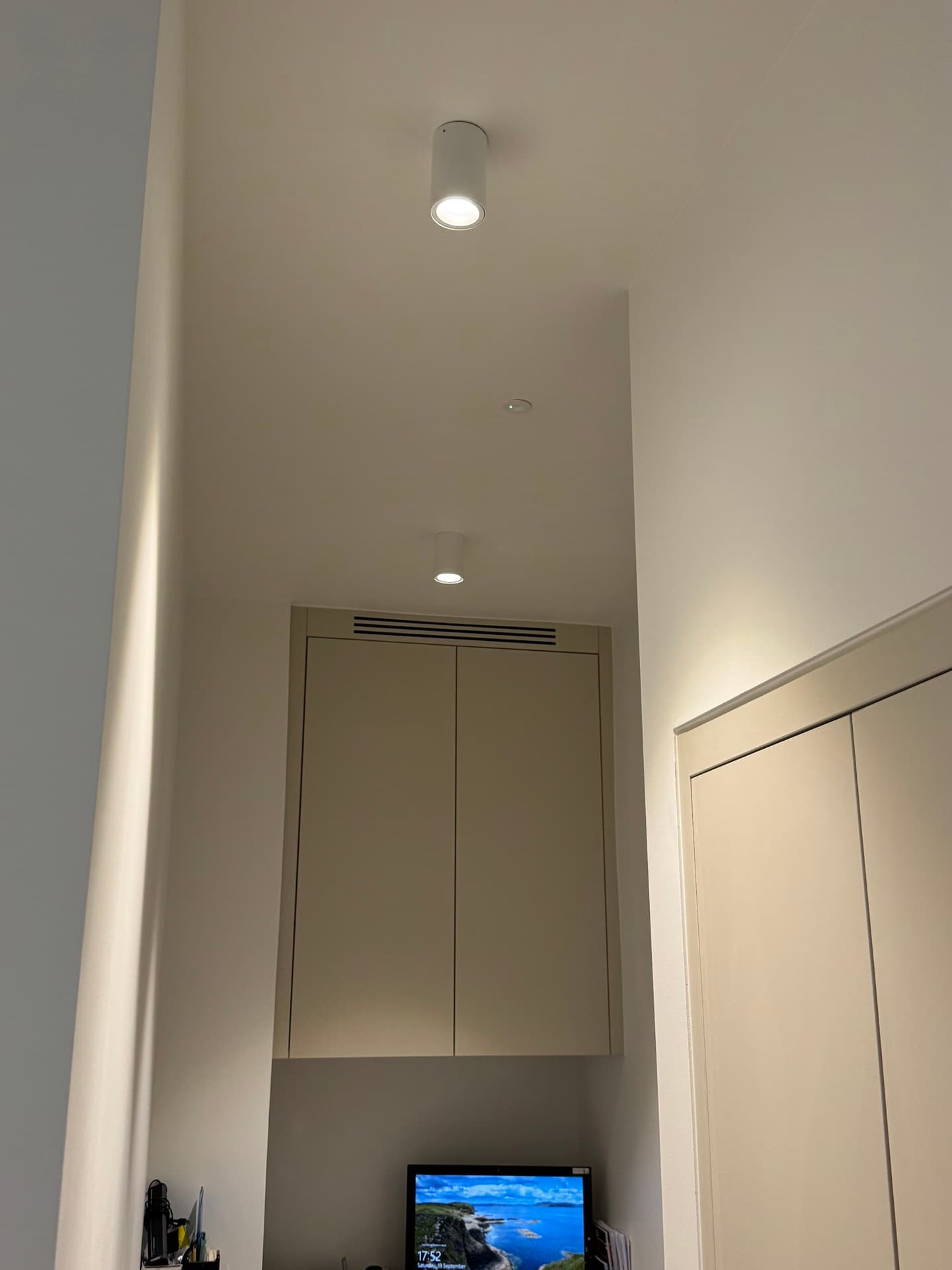 Dental treatment room with cylindrical wall-mounted downlights, recessed ceiling lighting, and wall-mounted display at Harcourt Dental Clinic