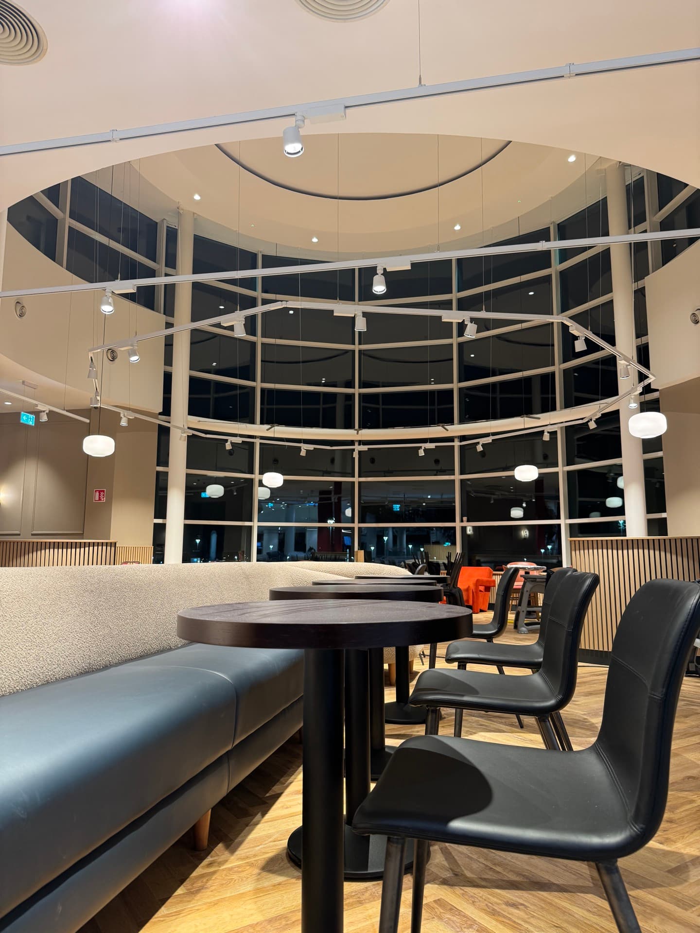 Curved storefront window with globe pendant lights and architectural ceiling lighting at Insomnia Liffey Valley