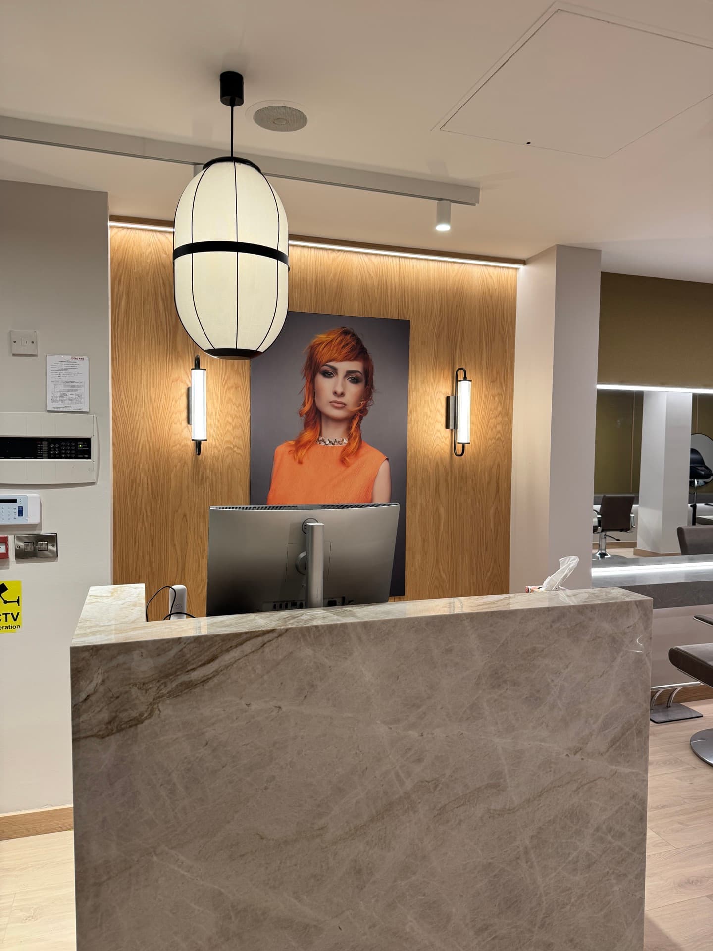 Zebra Hair Dressers reception desk with decorative pendant lamp and backlit product display wall